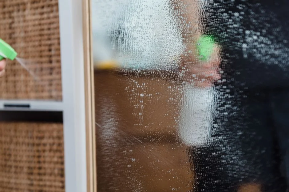 about-img-01 Close-up of a hand, wearing yellow gloves, cleaning an outdoor window with a squeegee.